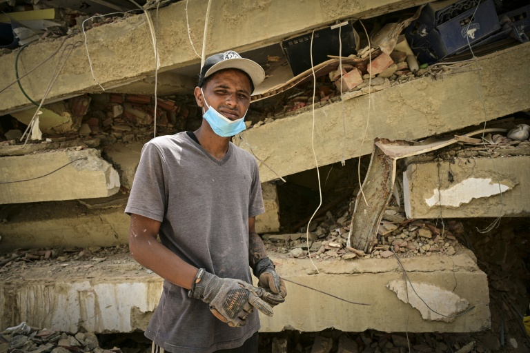 Raul Alvarado (g) cherche des proches disparus sous les décombres de l'immeuble OPP 26 de 16 étages ç Carabellada, dans l'Etat de La Guaira, le 6 juillet 2026 au Venezuela