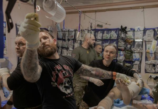 Anastassia Podobailo (d), son collègue et époux Mykola Iassinenko (2e g) et d'autres médecins militaires, soignent un soldat blessé dans un poste médical de la 56e brigade, dans la région de Donetsk, le 15 mars 2026 en Ukraine