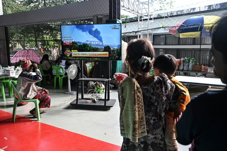 Des personnes déplacées par les combats à la frontière avec le Cambodge regardent les informations à la télévision dans un centre d'accueil à Surin (Thaïlande), le 11 décembre 2025
