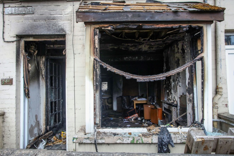 L'entrée et la fenêtre d'une maison brûlées après une deuxième nuit d'émeutes visant des immigrés à Ballymena, le 11 juin 2025 en Irlande du Nord