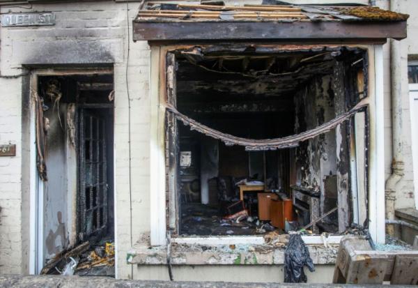 L'entrée et la fenêtre d'une maison brûlées après une deuxième nuit d'émeutes visant des immigrés à Ballymena, le 11 juin 2025 en Irlande du Nord