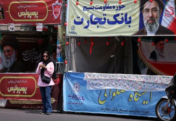 Une femme se tient sous une bannière représentant le guide suprême de l'Iran, l'ayatollah Mojtaba Khamenei, dans une rue de Téhéran, le 2 mai 2026