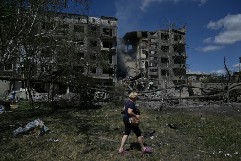 Une femme marche à Bilozerske, près de bâtiment bombardés par la Russie, le 12 août 2025