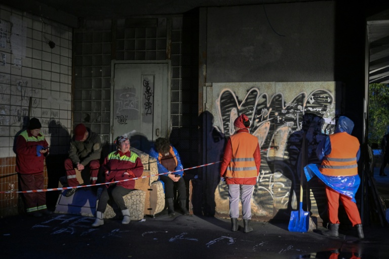 Des employés municipaux devant un immeuble résidentiel endommagé par des frappes massives de drones et de missiles russes à Kiev, le 10 octobre 2025