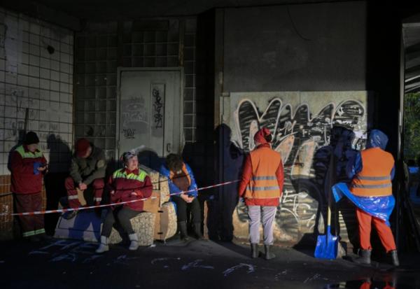 Des employés municipaux devant un immeuble résidentiel endommagé par des frappes massives de drones et de missiles russes à Kiev, le 10 octobre 2025