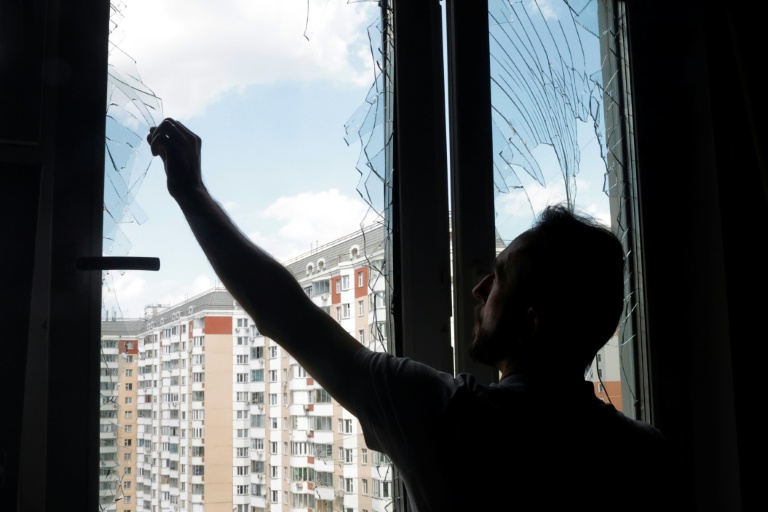 Un habitant retire des éclats de verre d’une fenêtre brisée dans un immeuble d'habitation après une attaque aérienne à Krasnogorsk, dans la région de Moscou, le 17 mai 2026