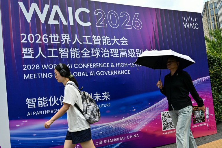 Des passants devant l'affiche de la Conférence mondiale sur l'intelligence artificielle (WAIC), le 16 juillet 2026 à Shanghai, en Chine