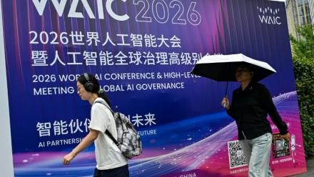Des passants devant l'affiche de la Conférence mondiale sur l'intelligence artificielle (WAIC), le 16 juillet 2026 à Shanghai, en Chine