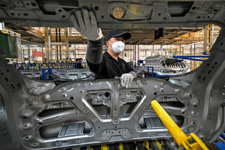 Un ouvrier manipule une pièce d'une voiture électrique dans une usine Zeekr sur l'île de Meishan à Ningbo, dans la province chinoise du Zhejiang, le 18 avril 2025