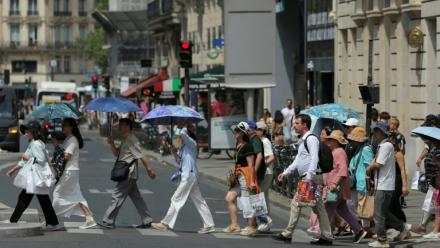 Des touristes se protègent du soleil sous des parapluies à Paris le 23 juin 2026