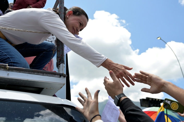 La cheffe de l'opposition au Venezuela, Maria Corina Machado (g), tend la main pour saluer ses partisans lors d'une manifestation à Caracas, le 17 août 2024