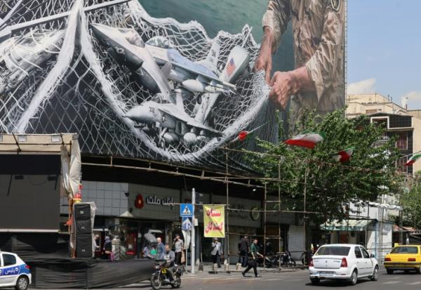 Des véhicules passent devant un immense panneau d'affichage sur lequel est écrit "Le détroit d'Ormuz reste fermé", sur la place de la Révolution à Téhéran, le 28 avril 2026, en Iran