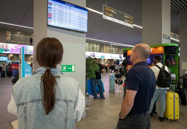 Des passagers regardent un panneau d'affichage des vols à l'aéroport de Kaliningrad, en Russie, le 4 juillet 2026